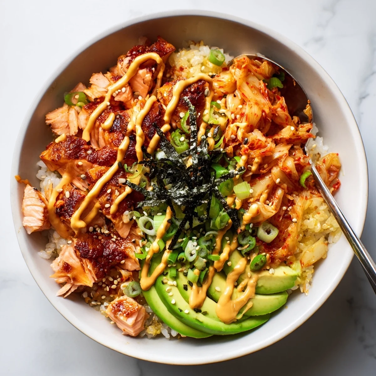 Crispy salmon rice bowl topped with spicy mayo, kimchi, and fresh avocado slices.  