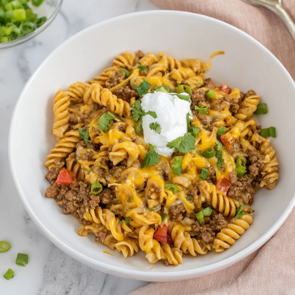 A hearty skillet of cheesy taco pasta, loaded with ground beef and melted cheddar cheese.