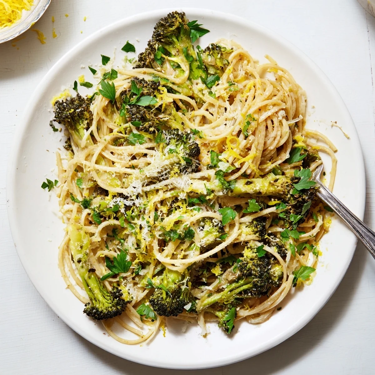 Steaming plate of roasted garlic lemon broccoli angel hair pasta, with fresh parsley and Parmesan cheese.