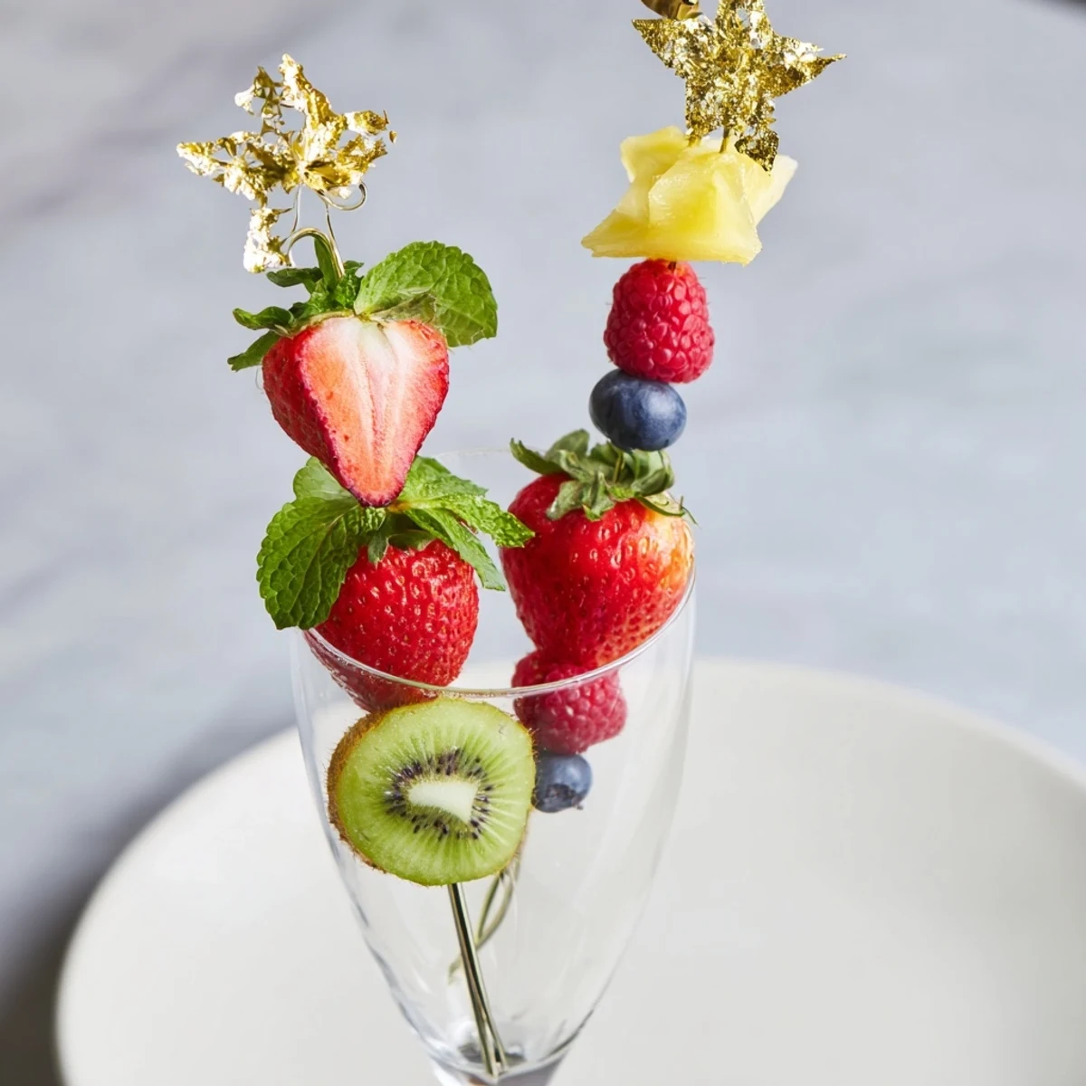Elegant champagne flute fruit garnishes, showcasing vibrant strawberries, kiwi slices, and pineapple wedges ready to serve.