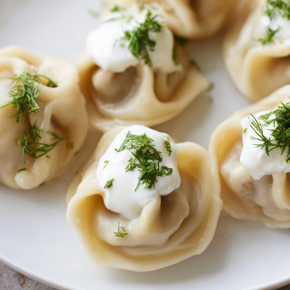 Steaming Russian pelmeni, perfectly formed, nestled in the bowl with a dollop of sour cream.