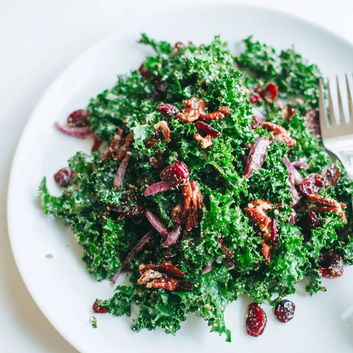A vibrant serving of Warm Kale Salad with sweet maple dressing, tossed with red onion slices and feta cheese crumbles.