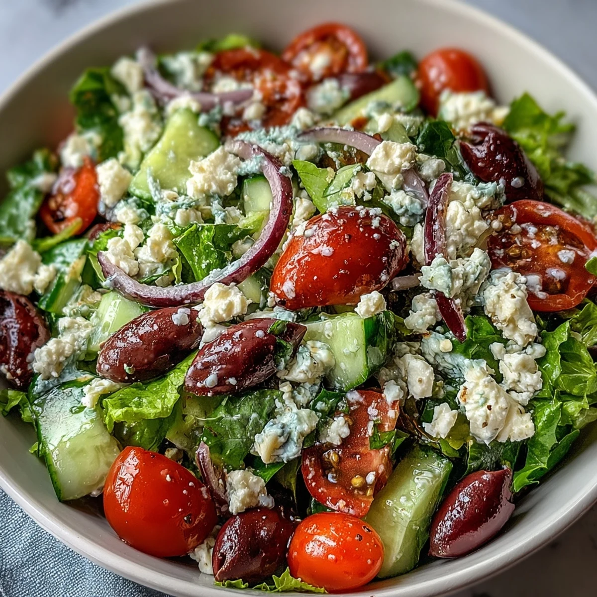 Fresh Mediterranean Green Salad Bowl with crisp lettuce, juicy tomatoes, and creamy feta topped with Greek dressing.