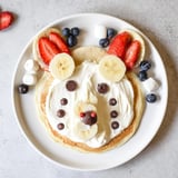 A vibrant brunch board showcases adorable Polar Bear Pancakes, strawberries, and drizzled maple syrup.