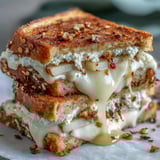 Golden-brown sourdough slices hugging melted chèvre and cream cheese, drizzled with honey and chili flakes.