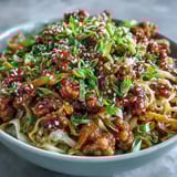 Steaming bowls of Potsticker Noodle Bowls feature tender noodles tossed with browned pork, crisp cabbage, and carrots in a savory sauce.