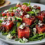 Fresh summer watermelon and arugula salad featuring crisp cucumber, red onion, and mint with tangy feta and pistachios.  