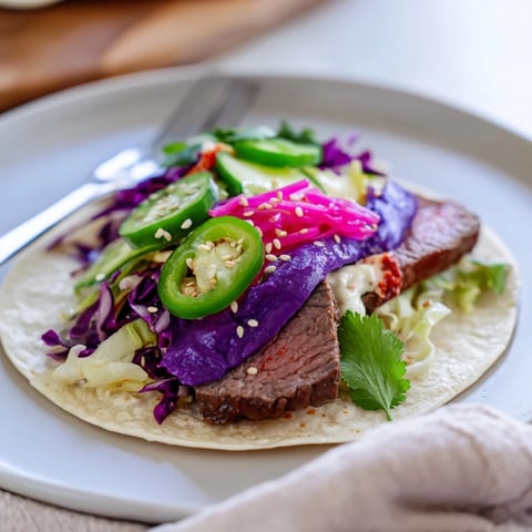 Colorful fusion tacos with Korean bulgogi and ube crema, bursting with flavor.