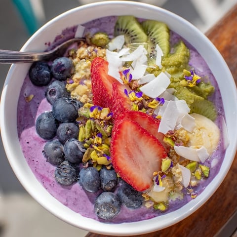 Vibrant smoothie bowls with pistachio and purple yam, topped with fresh berries.  