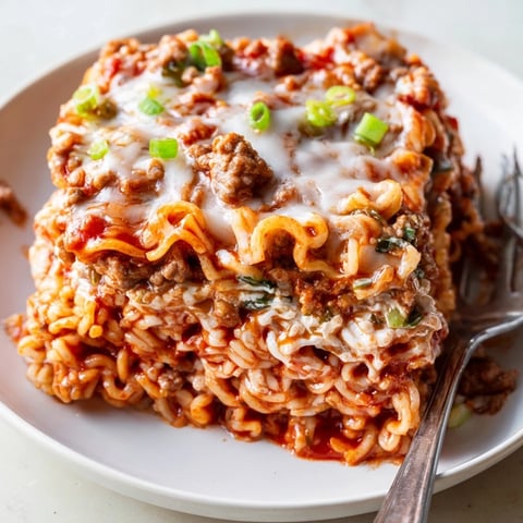 Spicy Ramen Lasagna layered with cheese, pork, and tangy tomato sauce delights the senses.  