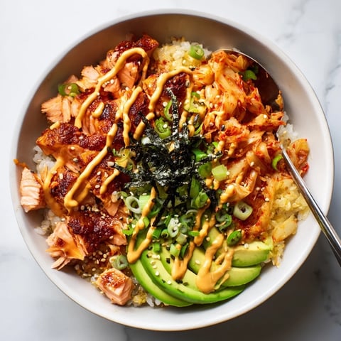 Crispy salmon rice bowl topped with spicy mayo, kimchi, and fresh avocado slices.  