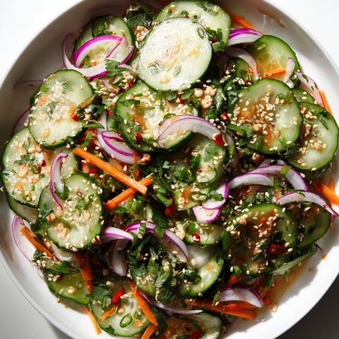 Vibrant Cucumber Salad Remix drizzled with sesame oil and fresh herbs, inviting summer flavors.  