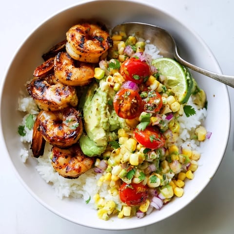 Vibrant easy grilled shrimp bowl topped with avocado corn salsa and lime.  