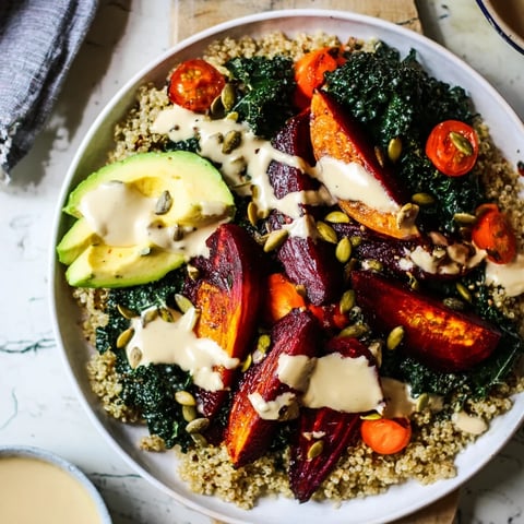 Vibrant quinoa, kale, and roasted beet bowl, drizzled with creamy tahini dressing, a healthy, colorful meal.