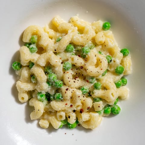Creamy macaroni and peas, a comforting bowl of pasta with melted Parmesan cheese.