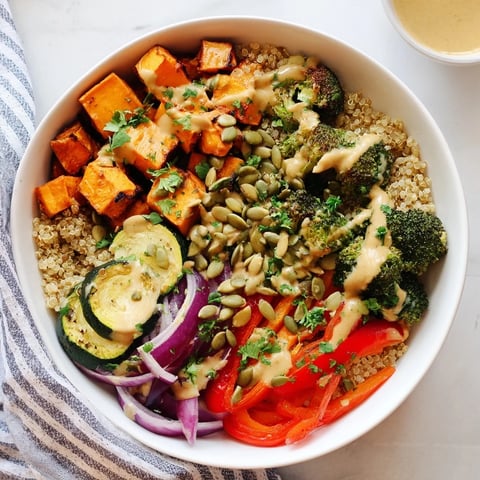 Warm quinoa bowl with roasted seasonal veggies, drizzled with creamy lemon-tahini dressing.