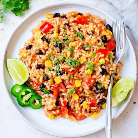 Steaming, vibrant One-Pot Mexican Rice & Beans, a colorful main dish with fresh cilantro and lime.