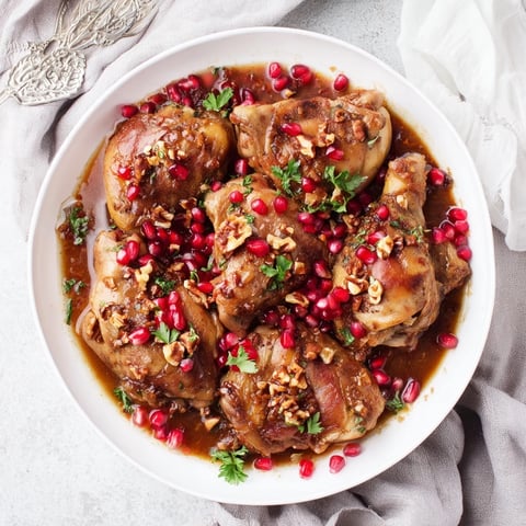 A steaming bowl of Pomegranate Walnut Fesenjan Stew with dark, glossy sauce and tender chicken.