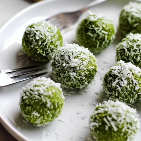 Vibrant photo of creamy Coconut Matcha Snowball Fat Bombs rolled in shredded coconut, ready to chill.