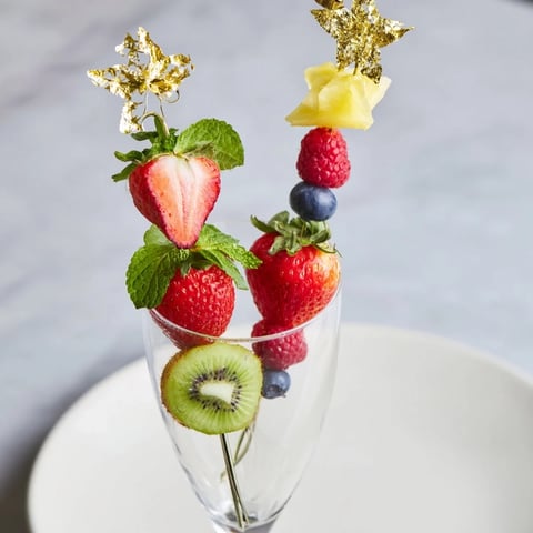 Elegant champagne flute fruit garnishes, showcasing vibrant strawberries, kiwi slices, and pineapple wedges ready to serve.