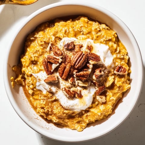 Steaming bowl of pumpkin spice latte oats with warm cinnamon and a swirl of creamy yogurt.