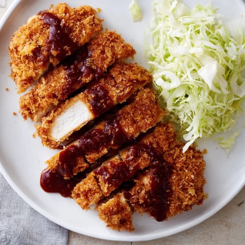 Golden-brown Chicken Katsu cutlet, served with tangy tonkatsu sauce, promises a delightful Japanese meal.