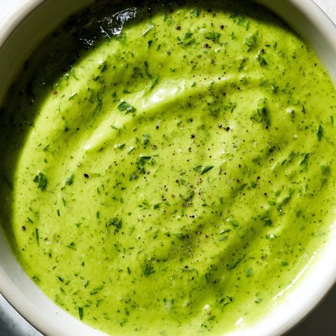 Vibrant green Green Goddess Dressing, creamy and herbaceous, ready to drizzle over a fresh salad.