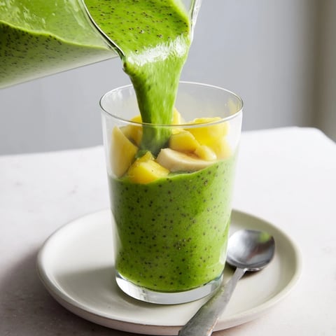 Creamy spinach-hidden smoothie with frozen mango and pineapple, a refreshing breakfast drink.