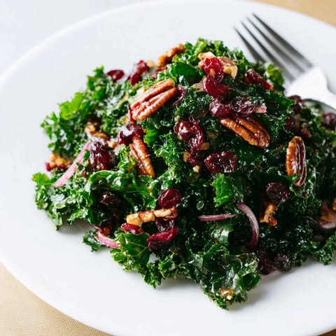 Freshly massaged kale leaves coated in a warm, glossy maple-mustard glaze, topped with crunchy toasted pecans and chewy dried cranberries.