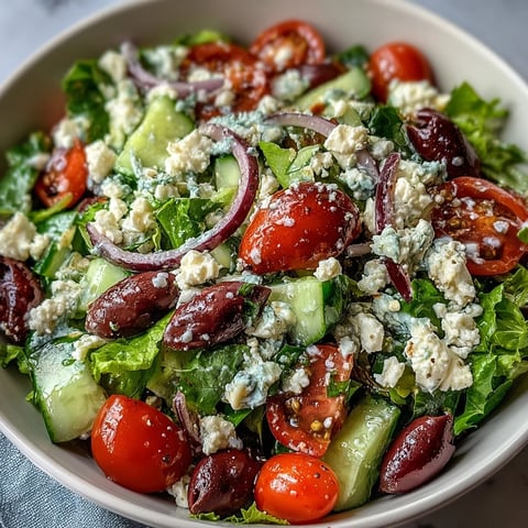 Fresh Mediterranean Green Salad Bowl with crisp lettuce, juicy tomatoes, and creamy feta topped with Greek dressing.