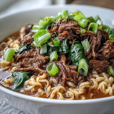 Slow cooker beef ramen noodles with tender shredded beef and a savory broth in a ceramic bowl.