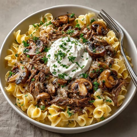 Juicy slow cooker beef stroganoff simmering in a rich, mushroom-infused cream sauce.