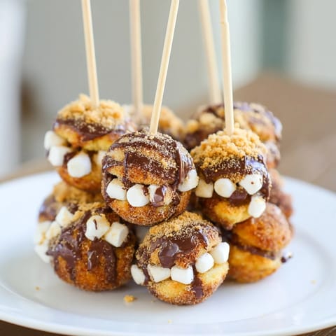 Deliciously gooey Smores Churro Cake Pancake Pops served warm with melted chocolate drizzle.  