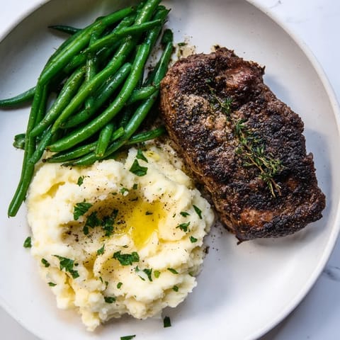 Sizzling steak and fluffy garlic mashed potatoes, roasted with green beans on a sheet pan.