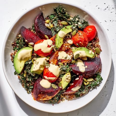 A close-up of a finished quinoa, kale, and roasted beet bowl; bursting with fresh ingredients, ready to eat.