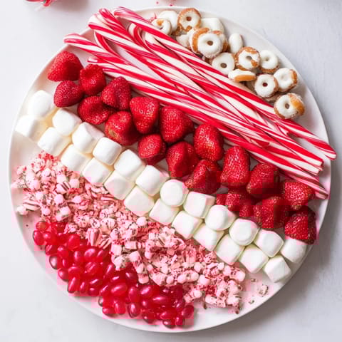 A beautiful Sweet Board featuring colorful candies, juicy strawberries, and creamy white chocolate pretzels.