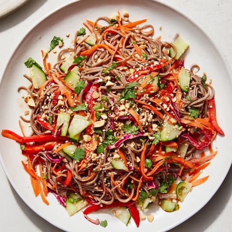 Vibrant cold noodle salad features sesame-ginger dressing with added peanuts for extra crunch and flavor.