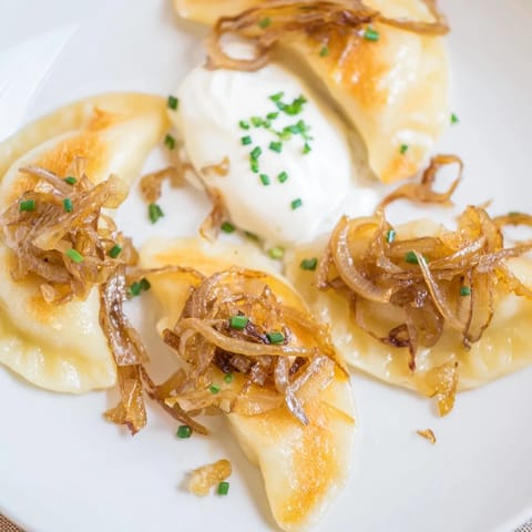 A close-up shows tender Polish pierogi with a creamy potato and cheese filling, perfect served.