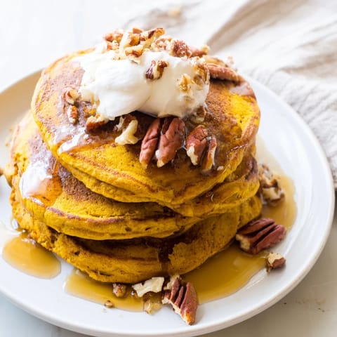 A stack of freshly cooked Pumpkin Spice Pancakes, showcasing their beautiful, spiced, pumpkin color.