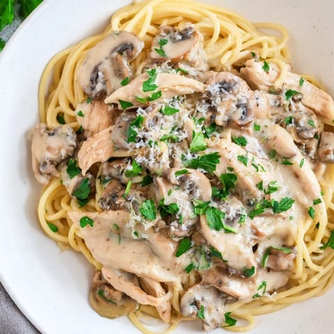 Creamy Mushroom Chicken Spaghettini in a white bowl, paired with a crisp salad and a glass of white wine.  