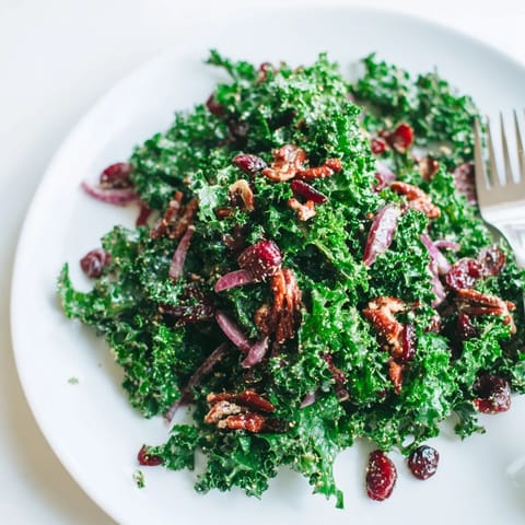A vibrant serving of Warm Kale Salad with sweet maple dressing, tossed with red onion slices and feta cheese crumbles.