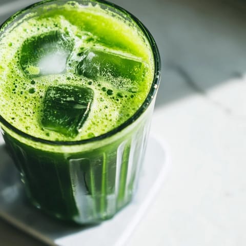 Bright green Cabbage and Kale Detox Juice in a mason jar, garnished with fresh ginger and celery for a refreshing sip.  