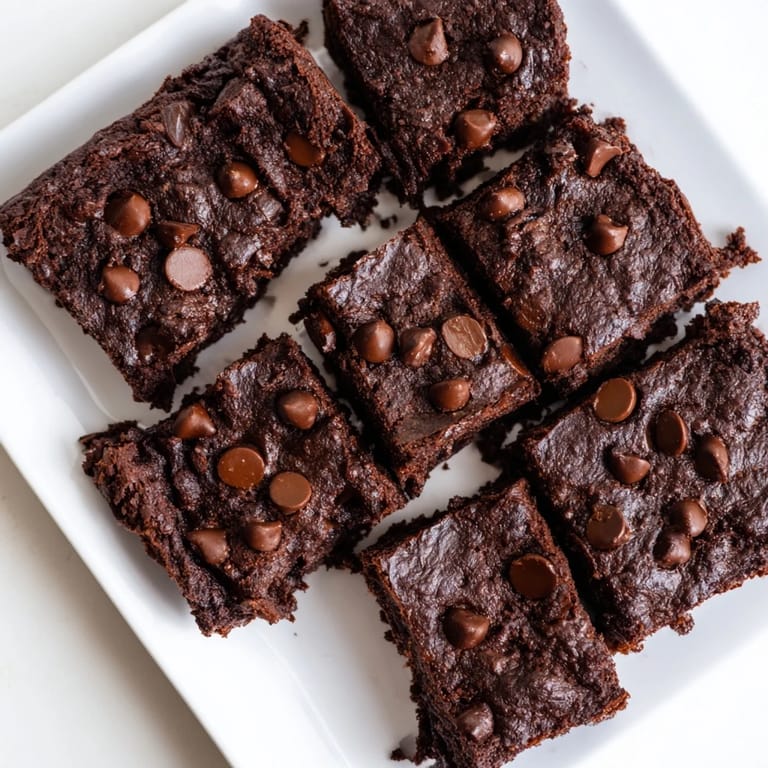Warm, dark Greek Yogurt Brownies with a slightly cracked top showcasing a moist, chocolatey interior.