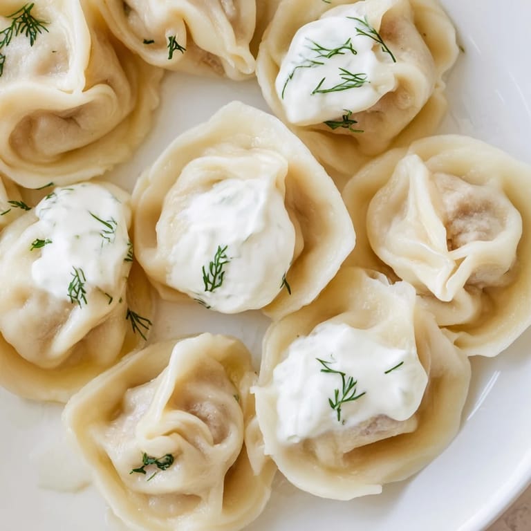 A close-up of golden Russian pelmeni, ready to eat, swimming in flavorful broth.