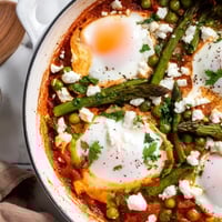 Bright green peas, tender broad beans, and asparagus nestled in a spiced tomato sauce with poached eggs in this vibrant Pea and Broad Bean Shakshuka.