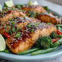 Golden-brown Sheet Pan Teriyaki Salmon with Broccoli and Snap Peas, glazed and served with jasmine rice and lime wedges.