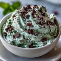 Creamy mint chocolate chip dip served with graham crackers and fresh fruit for a festive St. Patrick's Day treat.