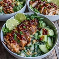 A close-up of TikTok Chili-Crisp Cucumber Chicken Bowls, featuring sliced seared chicken and crisp cucumbers in creamy yogurt sauce.
